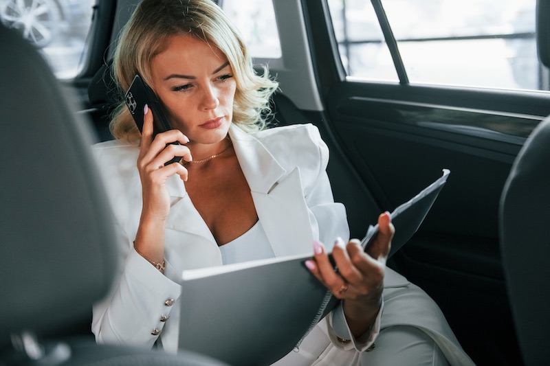 Vehicle interior. Woman in formal clothes is indoors in the autosalon